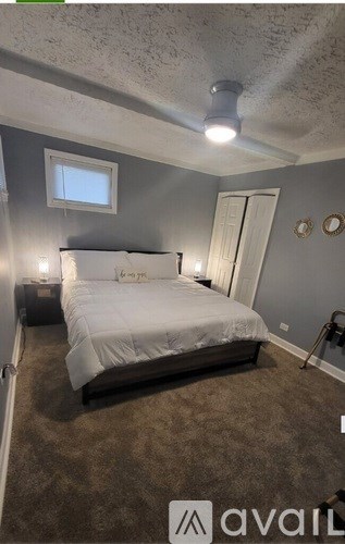 A bedroom with a bed, two wall lamps, and a window.