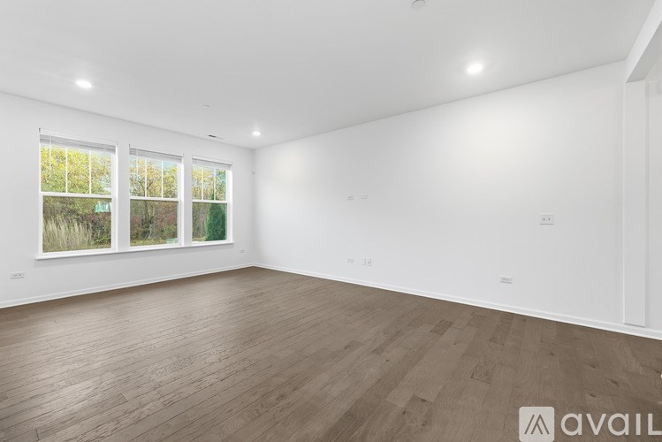 A spacious room with wooden flooring and a large window.
