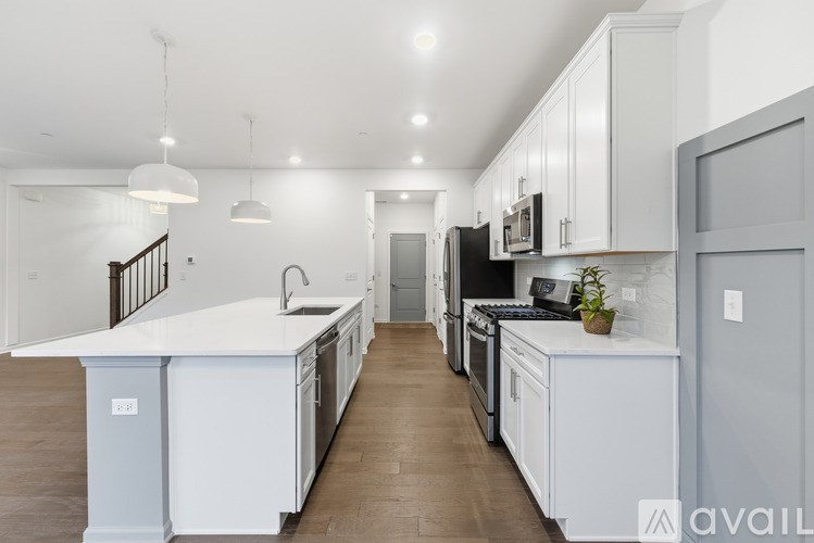 A modern kitchen with white cabinets and a wooden floor.