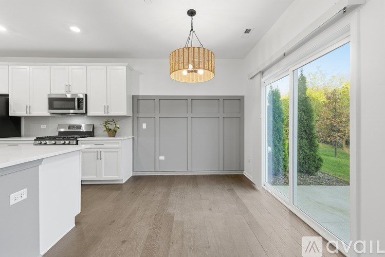 A modern kitchen with white cabinets and a wooden pendant light.