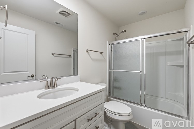 A white bathroom with a glass shower door and a white toilet.