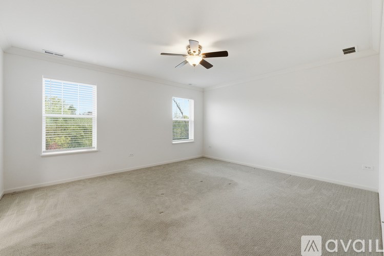 A room with a ceiling fan and two windows.