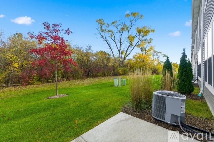 A red tree stands in a yard next to a building.