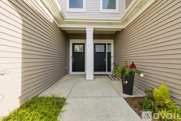 A house entrance with a black door and a white pillar.