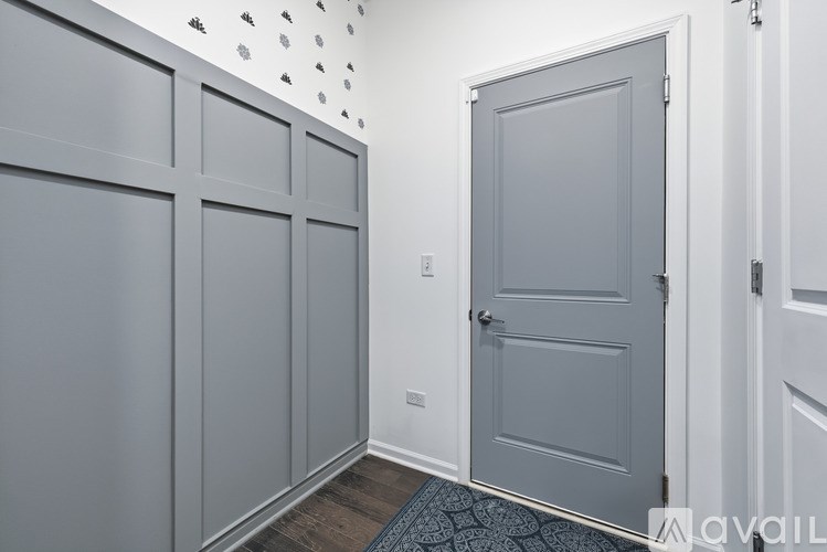 A hallway with a grey door and a white wall with a black and white pattern.