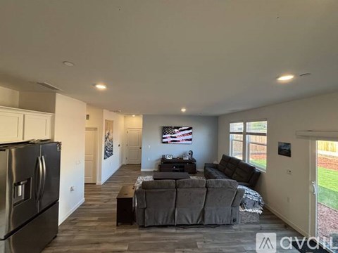 A living room with a grey couch and a black refrigerator.