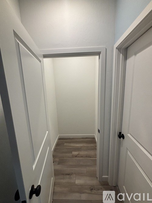 A hallway with white doors and a wooden floor.