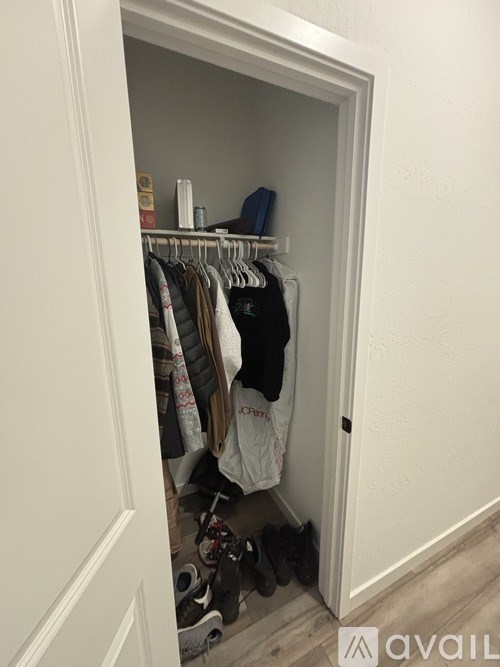 A white closet with clothes hanging on a rack.