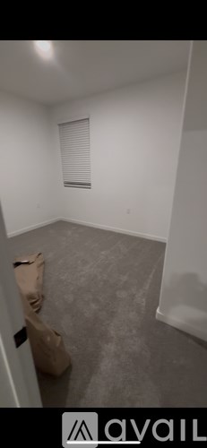 A room with a carpeted floor and a window with blinds.