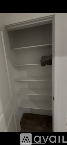 A white empty cabinet with a towel hanging on the door.