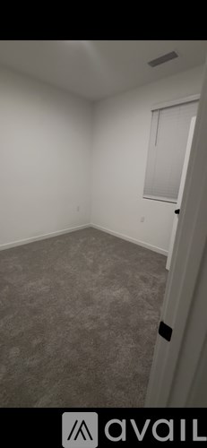 A room with a carpeted floor and a window with blinds.