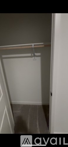 A small, empty room with a white door and a grey wall.