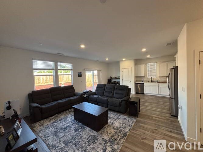 A living room with a black leather couch and a coffee table in the center.