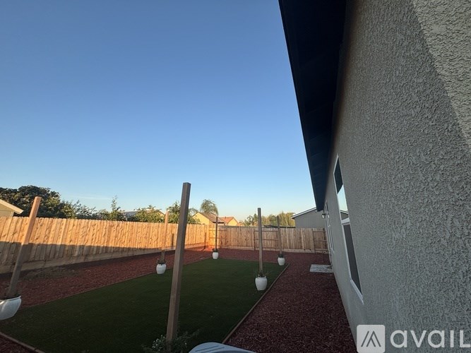 A backyard with a wooden fence and a red brick pathway.