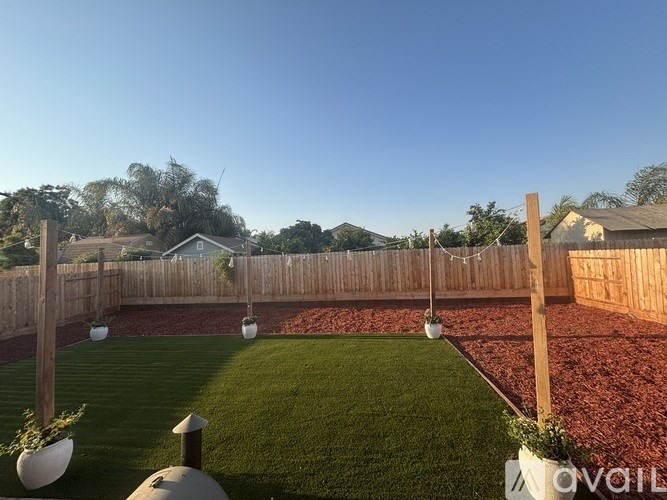 A backyard with a wooden fence and a green lawn.