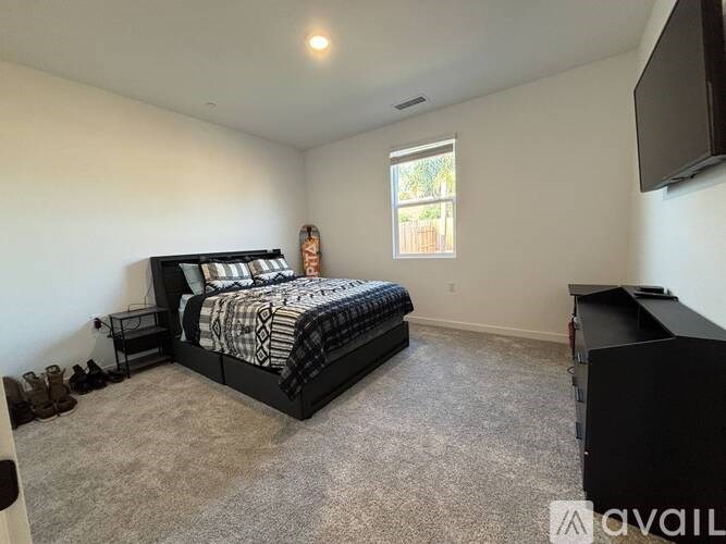 A bedroom with a bed, a television, and a window.
