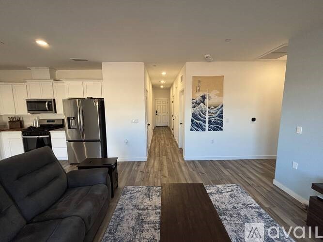 A living room with a black couch and a kitchen area with stainless steel appliances.