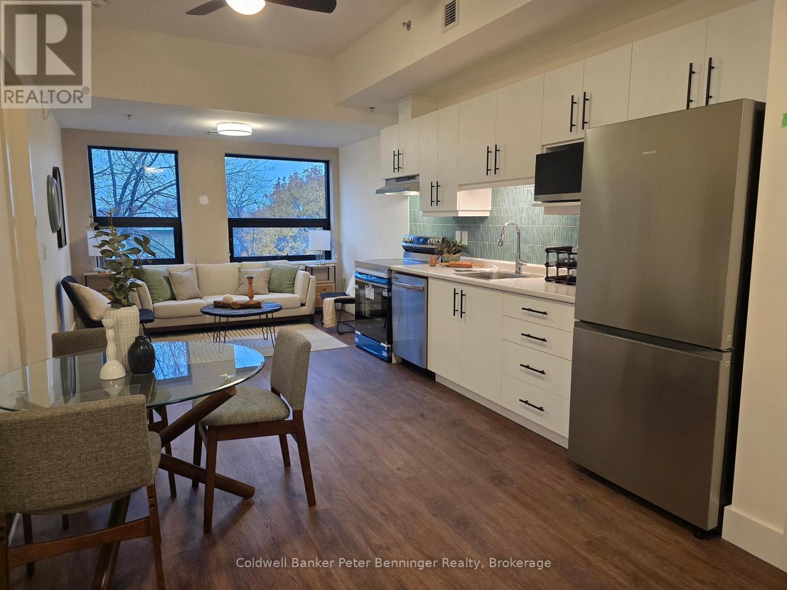 A kitchen with a refrigerator, sink, and dining table.