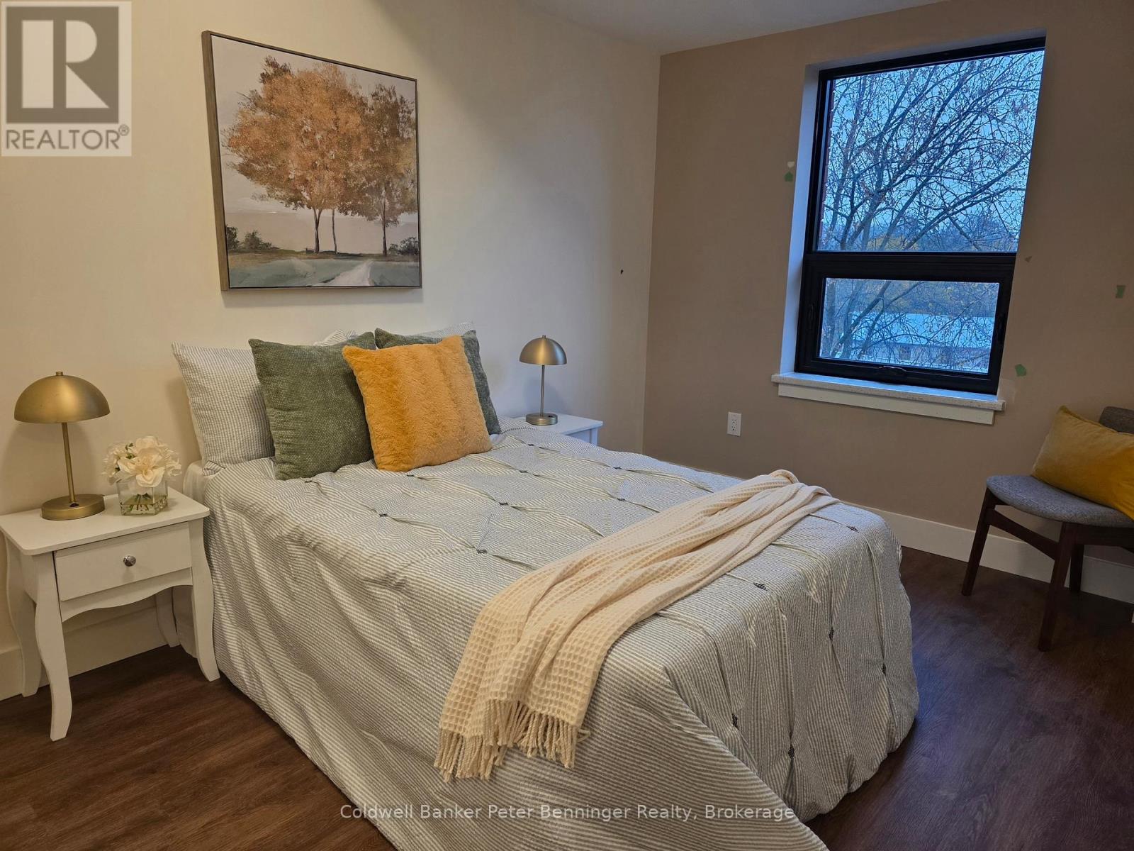 A bedroom with a bed, nightstand, and window.