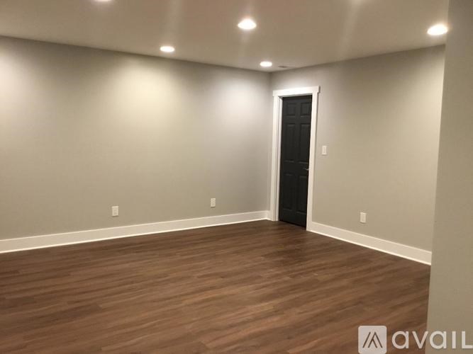 A room with a wooden floor and a black door.