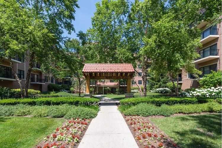 A garden with a walkway and a pavilion surrounded by trees.