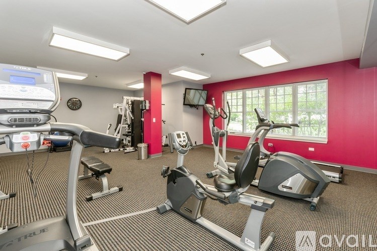 A gym with a variety of equipment including a treadmill, stationary bike, and weight machines.