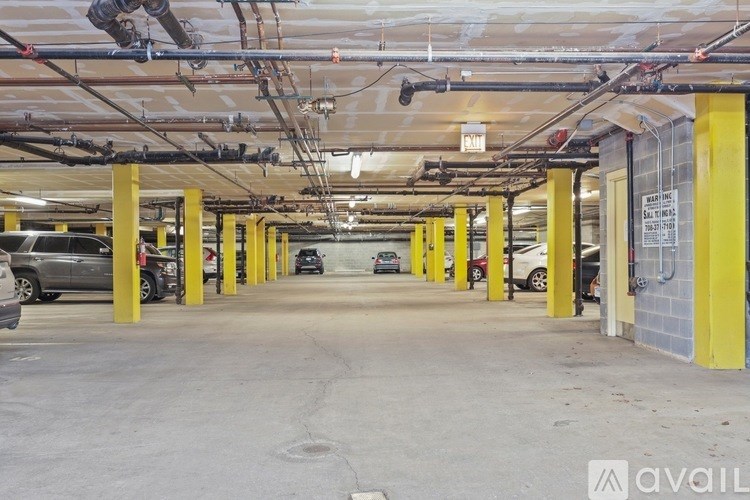 A parking garage with yellow pillars and cars parked in the background.