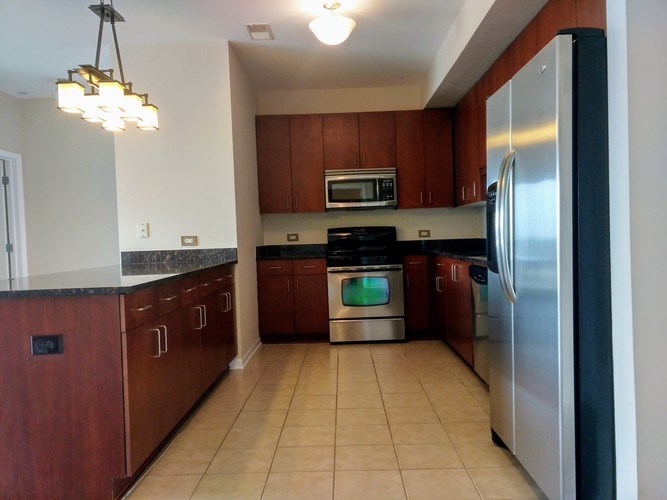 A kitchen with brown cabinets and a stainless steel refrigerator.