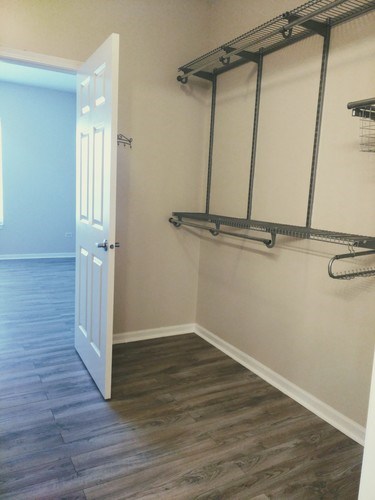 A white door is open to a hallway with a shelving unit on the wall.