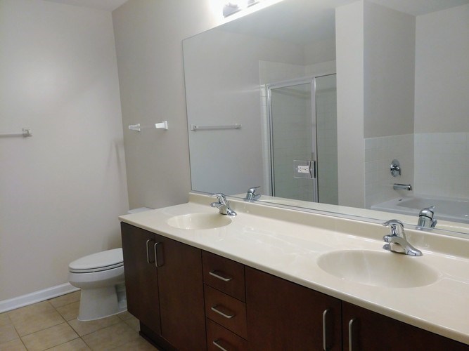A bathroom with a toilet, sink, and mirror.