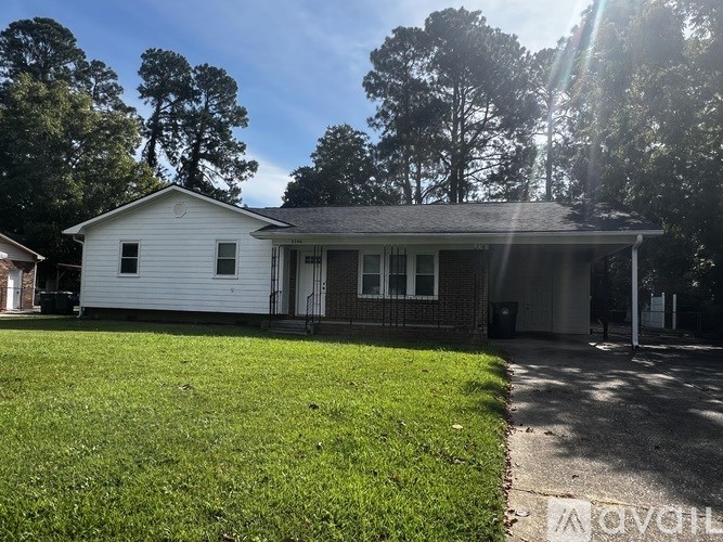 A white house with a grey roof and a green lawn in front.