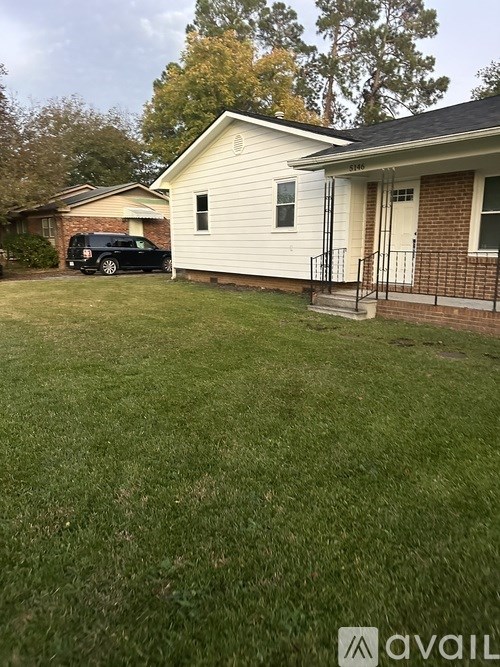 A house with a white exterior and a black car parked in the driveway.