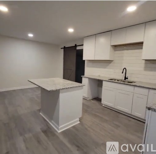 A kitchen with white cabinets and a marble island.