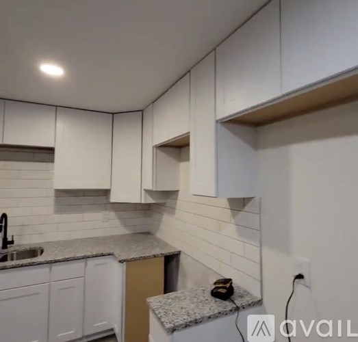 A kitchen with white cabinets and a granite countertop.