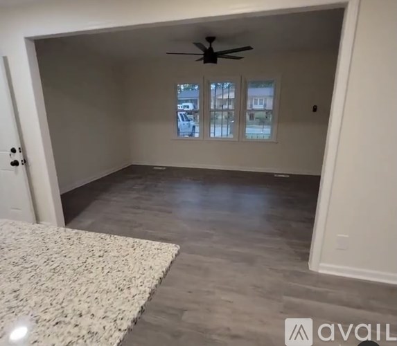 A room with a ceiling fan and a rug on the floor.