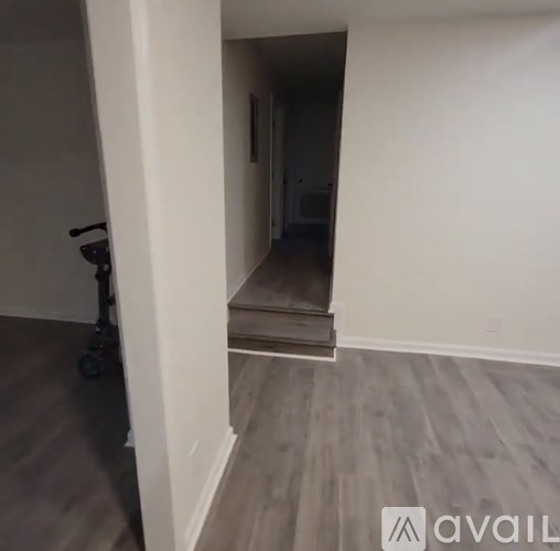 A room with a wooden floor and a wall with a doorway.