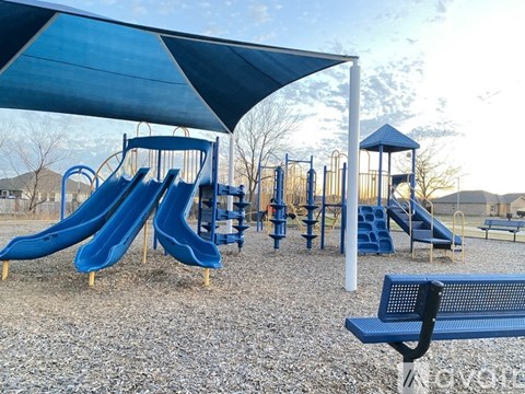 A playground with a blue slide and a blue canopy.