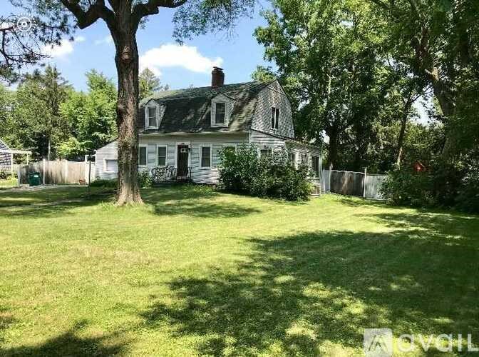 A house with a white fence and a tree in front of it.