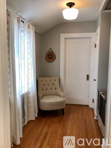 A white chair with buttons is in a room with wooden floors and white walls.