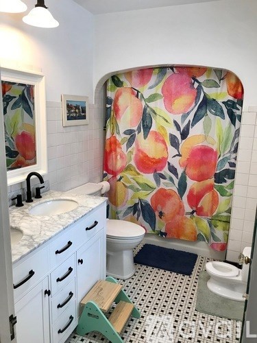A bathroom with a floral shower curtain and a white toilet.
