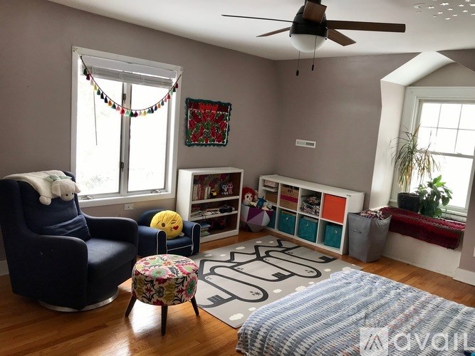 A living room with a blue chair and a rug with the letters "S" and "G" on it.
