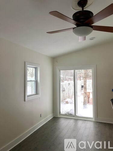 A room with a ceiling fan and two windows.