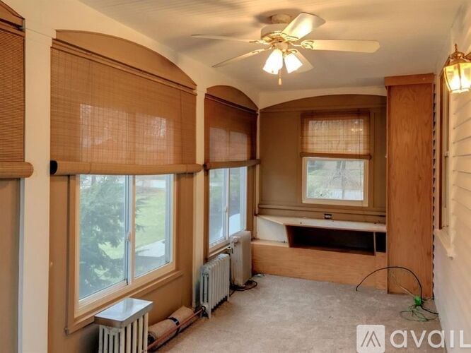 A room with a ceiling fan and a window with blinds.