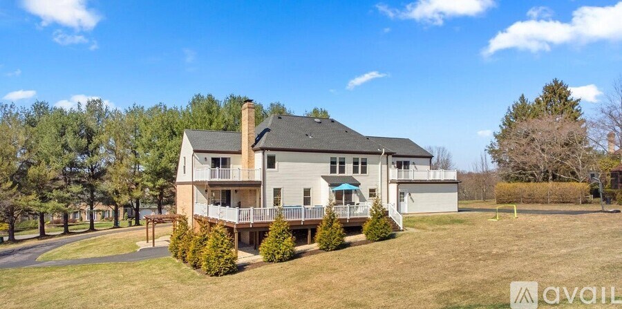 A large house with a balcony and a deck is surrounded by trees.