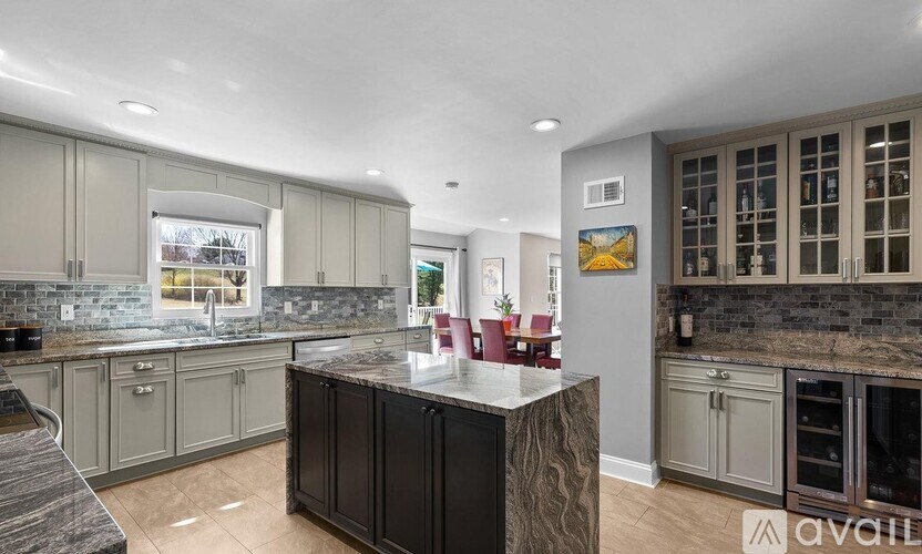 A modern kitchen with a dark granite countertop and grey cabinets.