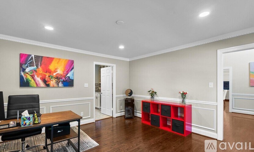 A room with a painting on the wall and a red shelf.