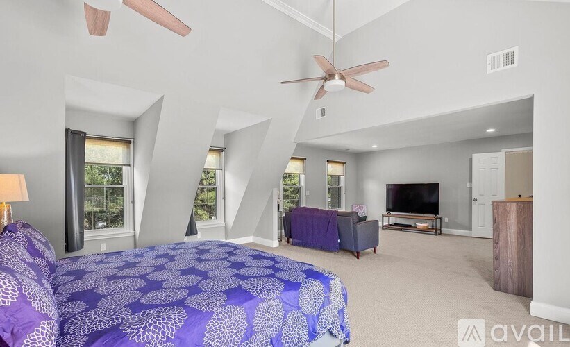 A bedroom with a purple bedspread and a ceiling fan.