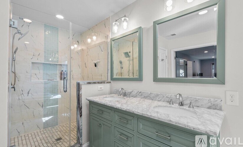 A bathroom with a marble countertop and green cabinets.