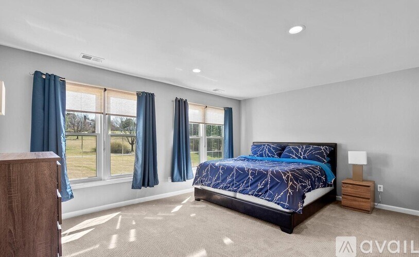 A bedroom with a large bed and a window with blue curtains.