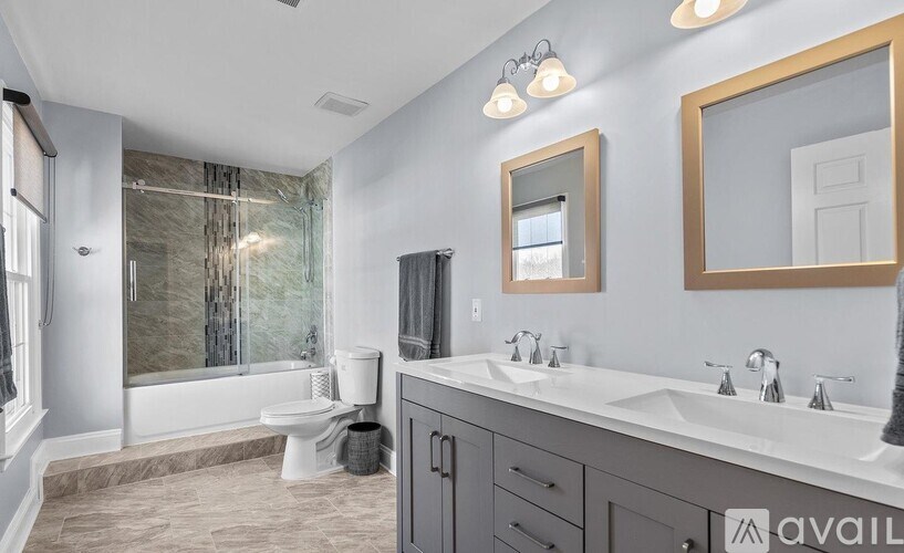 A bathroom with a walk-in shower, a toilet, a sink, and a mirror.